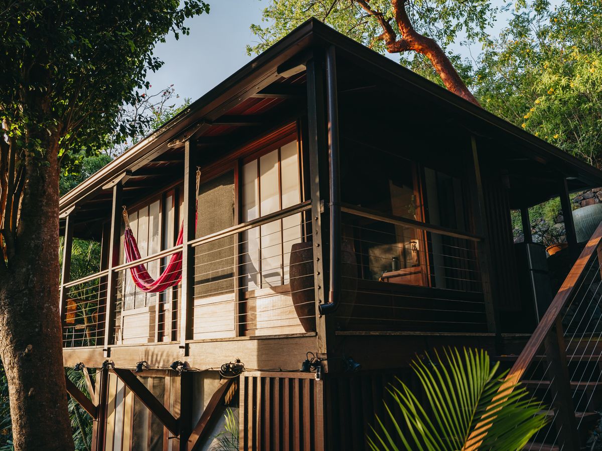 Teahouse Treehouse raised wooden cabin with a red hammock on the deck in the tropical forest