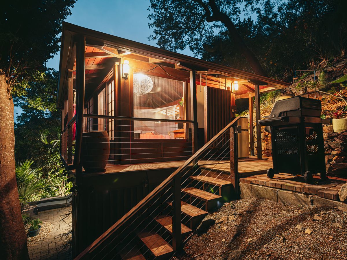 Teahouse Treehouse lit up at night with wooden stairs and deck