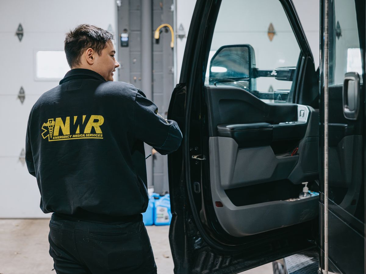 Northwest Rescue EMT opening the driver door of an ambulance in the station