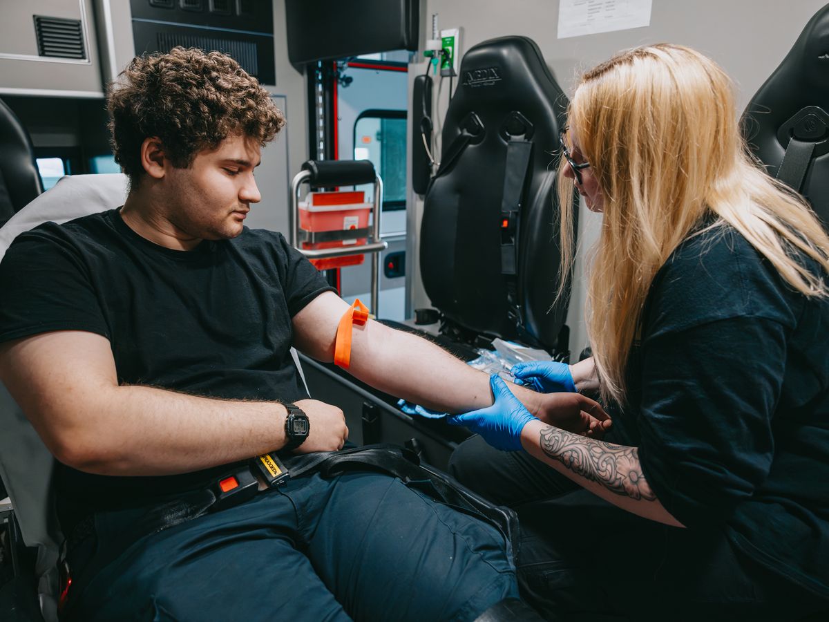 Northwest Rescue EMT starting an IV on a patient's arm inside the ambulance