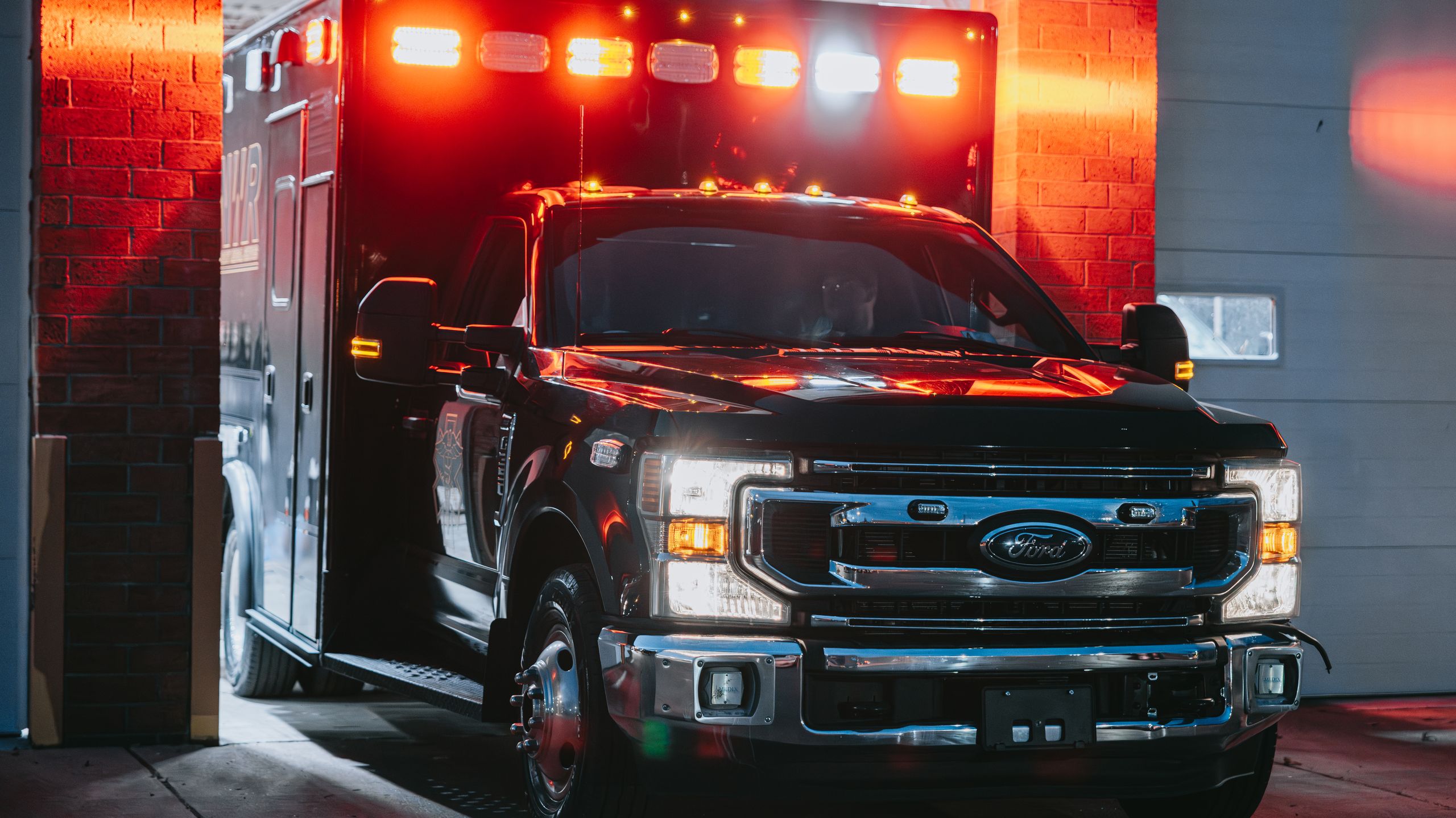 Northwest Rescue ambulance with emergency lights on in the station bay at night