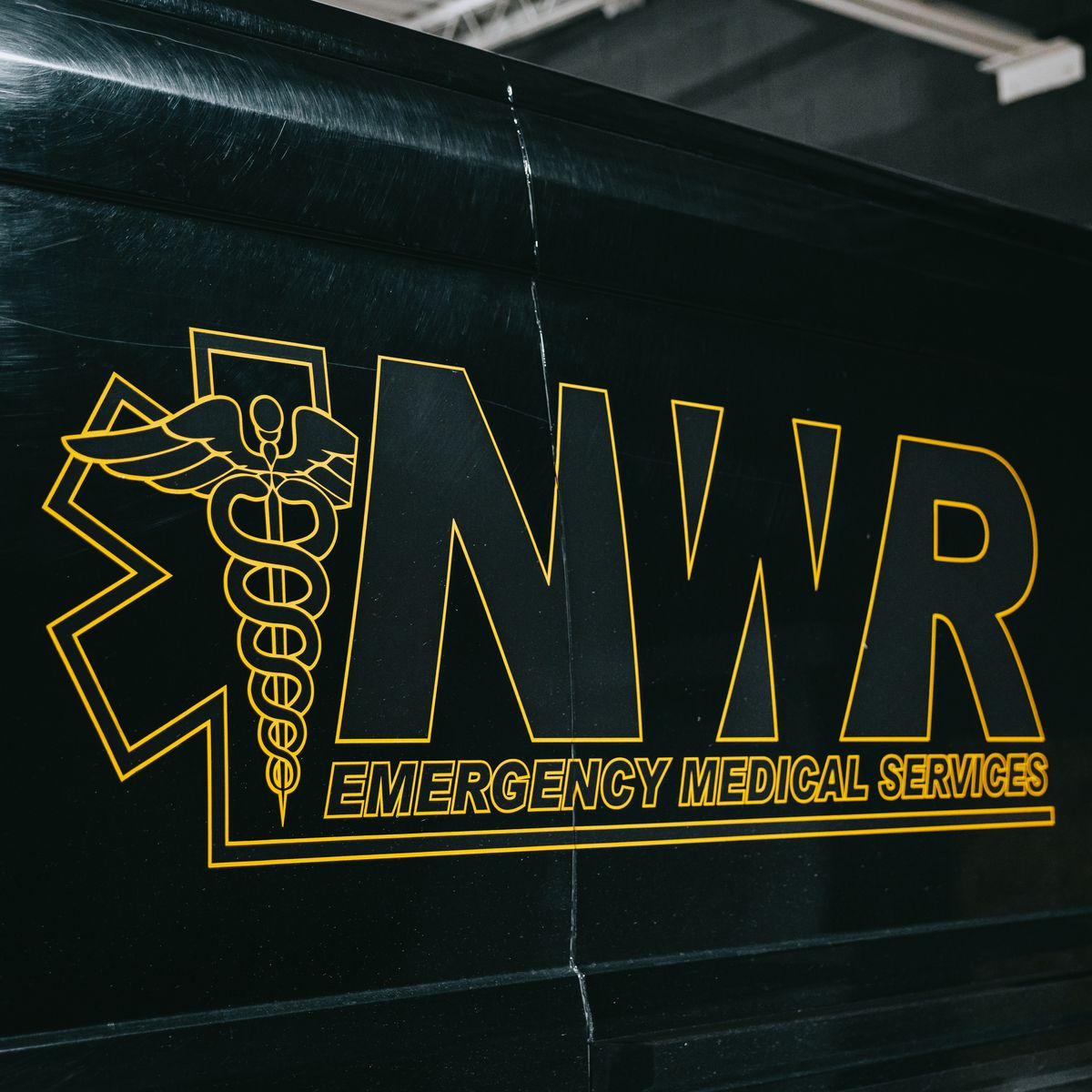Northwest Rescue gold star of life and NWR logo decal on the side of a black ambulance