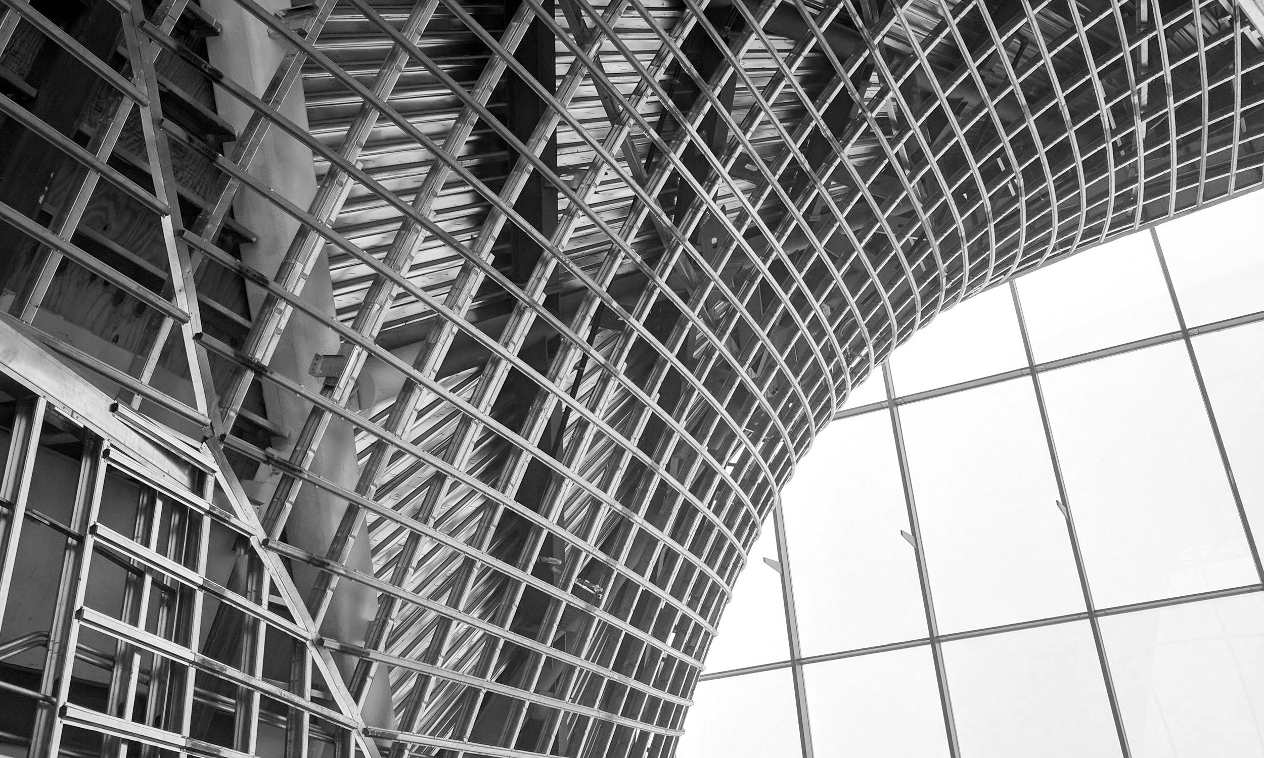 Curved freeform architectural metal wall framing made cold-formed light gauge metal framing and glass panels.