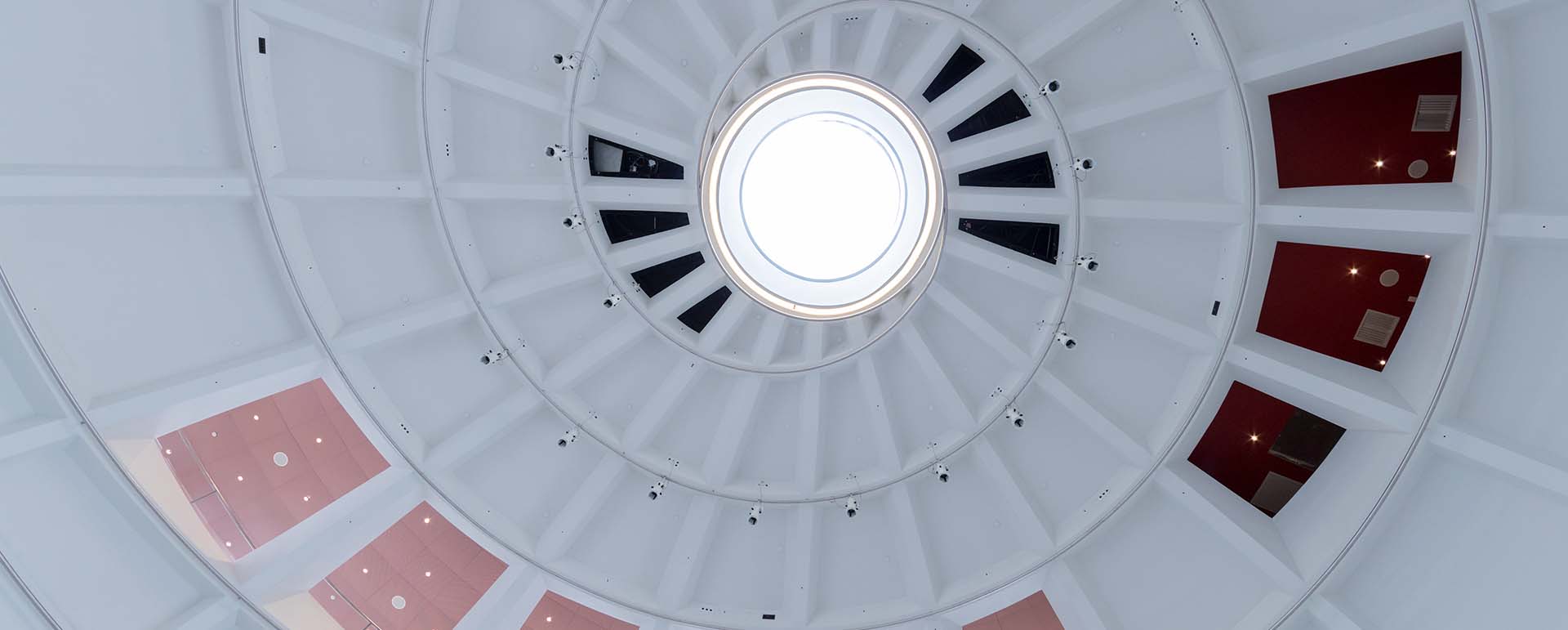 View looking up inside a white spiral dome ceiling with a circular skylight at the top, Faena Forum, Miami Florida