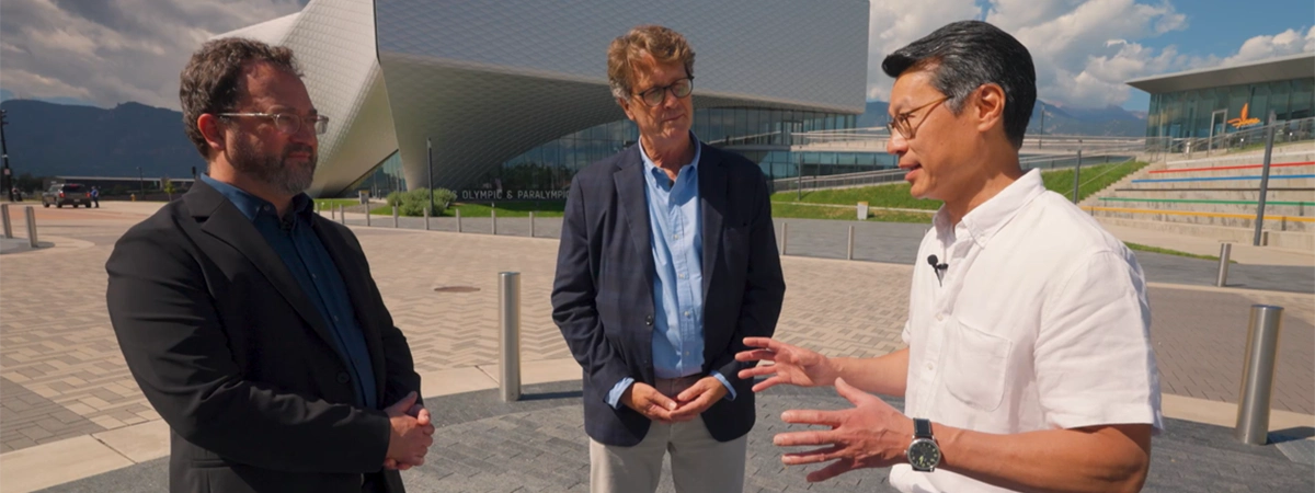 Three men, architects, standing outside a modern building (US Olympic and Paralympic Museum) having a conversation on a sunny day.