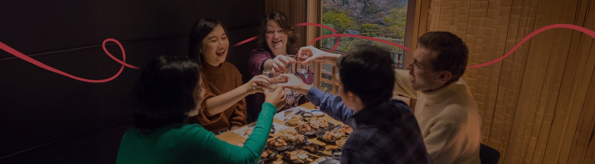 Group of friends enjoying a traditional Japanese meal together, raising their glasses in a cheerful toast