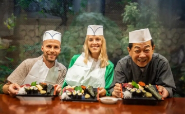 Happy participants posing with sushi they made during a sushi-making class in Japan