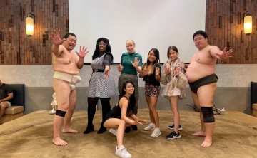Group of visitors posing with sumo wrestlers after an interactive sumo experience in Japan