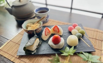 Traditional Japanese sweets (wagashi) beautifully arranged with matcha and tea set, featuring strawberry daifuku, dango, and mochi.