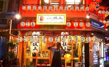 Vibrant izakaya decorated with traditional lanterns in Osaka at night.