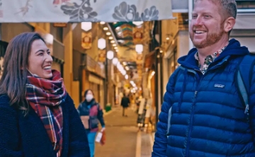 Two travelers laughing together while exploring a traditional Japanese shopping street