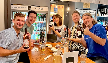 Friends enjoying a sake tasting experience at a local Japanese bar