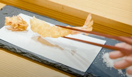 Freshly fried shrimp tempura being picked up with chopsticks