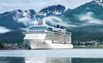 A majestic cruise ship anchored near snow-capped mountains and misty forests, offering a serene and scenic voyage