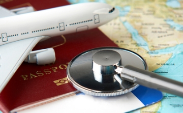 A stethoscope, passport, and airplane model placed on a world map, symbolizing travel health and international journeys