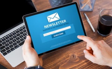 Person holding a tablet displaying a blue newsletter subscription page