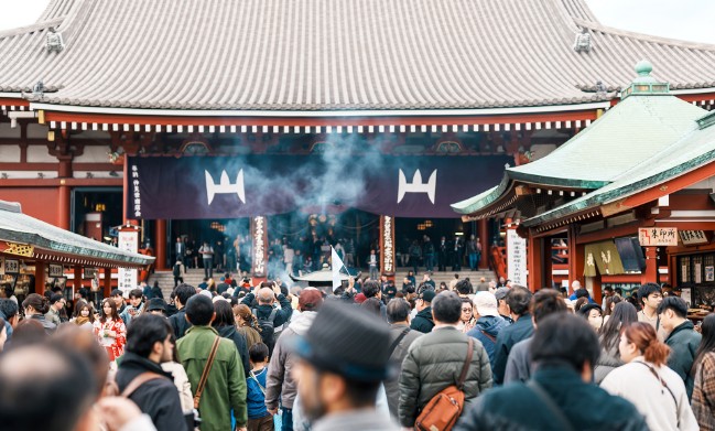 A large group of volunteers participating in the JTB Brighter Earth Project in Hawaii, gathering outdoors under a bright blue sky to promote environmental awareness.