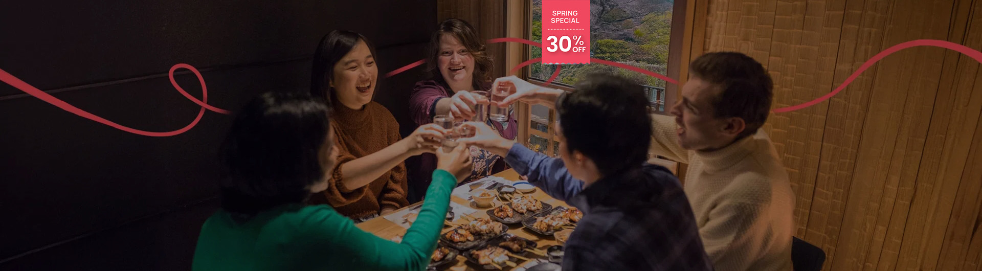 Group of friends enjoying a traditional Japanese meal together, raising their glasses in a cheerful toast