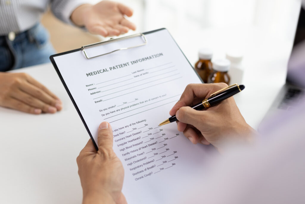 Patient filling out a medical information form at the dentist's office. The answer to, “How much is a clean at the dentist?” can vary depending on your medical history.