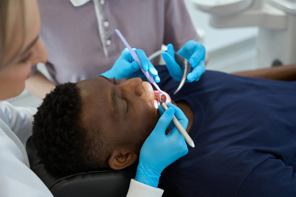 Patient receiving a dental cleaning from a dentist and hygienist. While teeth cleaning costs generally fall between $150 and $400, they can vary.