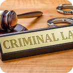 Gavel and stethoscope next to a plaque labeled 'CRIMINAL LAW' on a wooden desk.