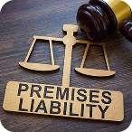 Wooden sign with scales of justice and the text 'Premises Liability' next to a gavel on a wooden surface.