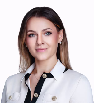 Portrait of a woman with long hair wearing a white blazer and black shirt, smiling softly against a white background.
