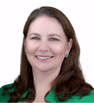 Smiling woman with long brown hair wearing turquoise earrings and a green top against a white background.