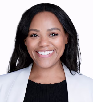 Smiling woman with long black hair wearing a white blazer and black top.