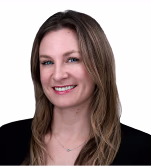 Smiling woman with long light brown hair wearing a black blazer and black top against a white background.