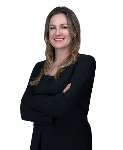 Smiling woman with long light brown hair wearing a black blazer and dark blue top against a white background.