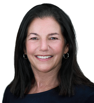 Smiling woman with long brown hair wearing a black blazer and pearl earrings against a white background.