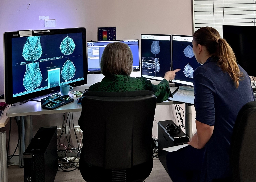 Radiologist reviewing breast images on diagnostic monitors in a clinical setting
