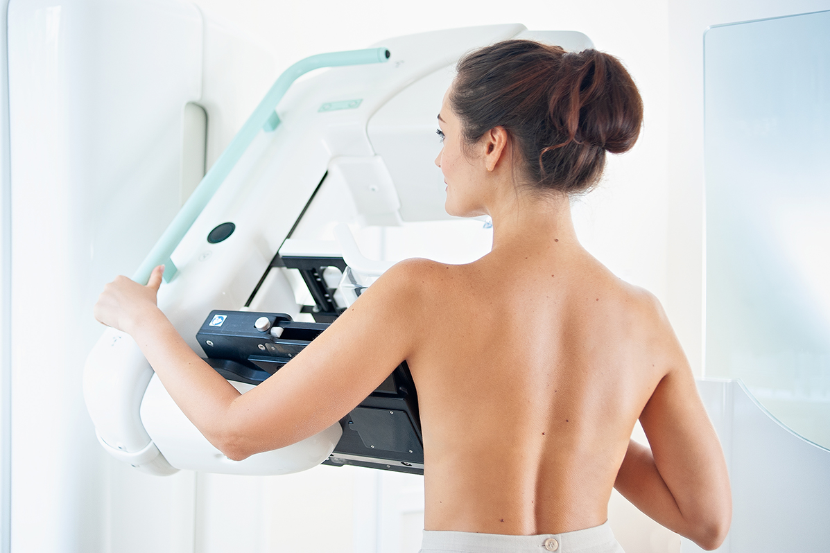 woman standing at a mammogram machine getting tested