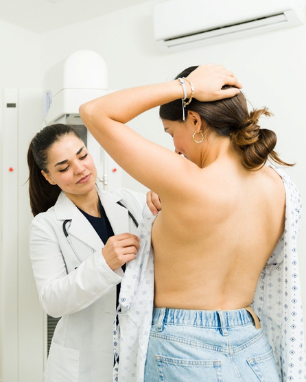 Doctor examining a woman’s breast as part of a clinical assessment