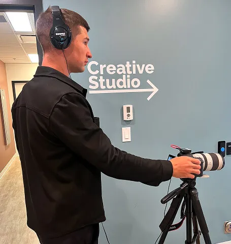 Behind-the-scenes view of Media&Motion capturing video in a Calgary creative studio, with the videographer monitoring audio and camera setup.