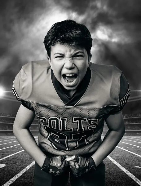 High-energy black-and-white portrait of a Calgary youth football player from the Colts team, captured during a Media&Motion Media Day with a dramatic stadium backdrop.