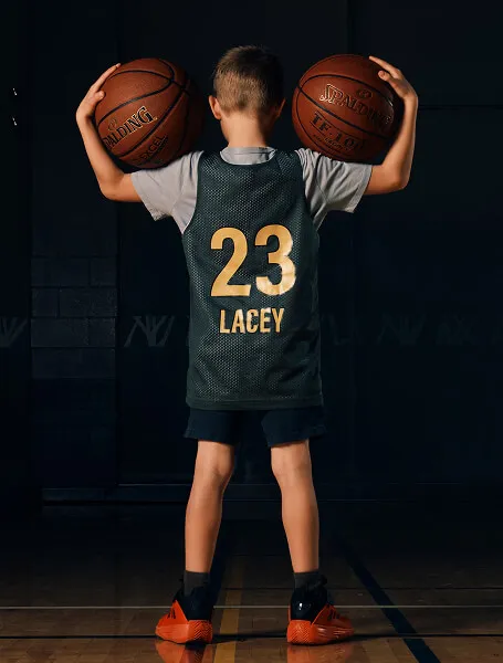 Back-view portrait of a Calgary youth basketball player holding two balls during a HoopStrength Media Day photoshoot by Media&Motion.