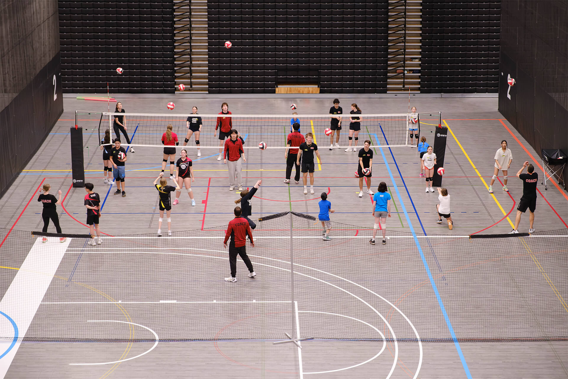 Multiple volleyball groups training simultaneously during large-scale youth sport program.