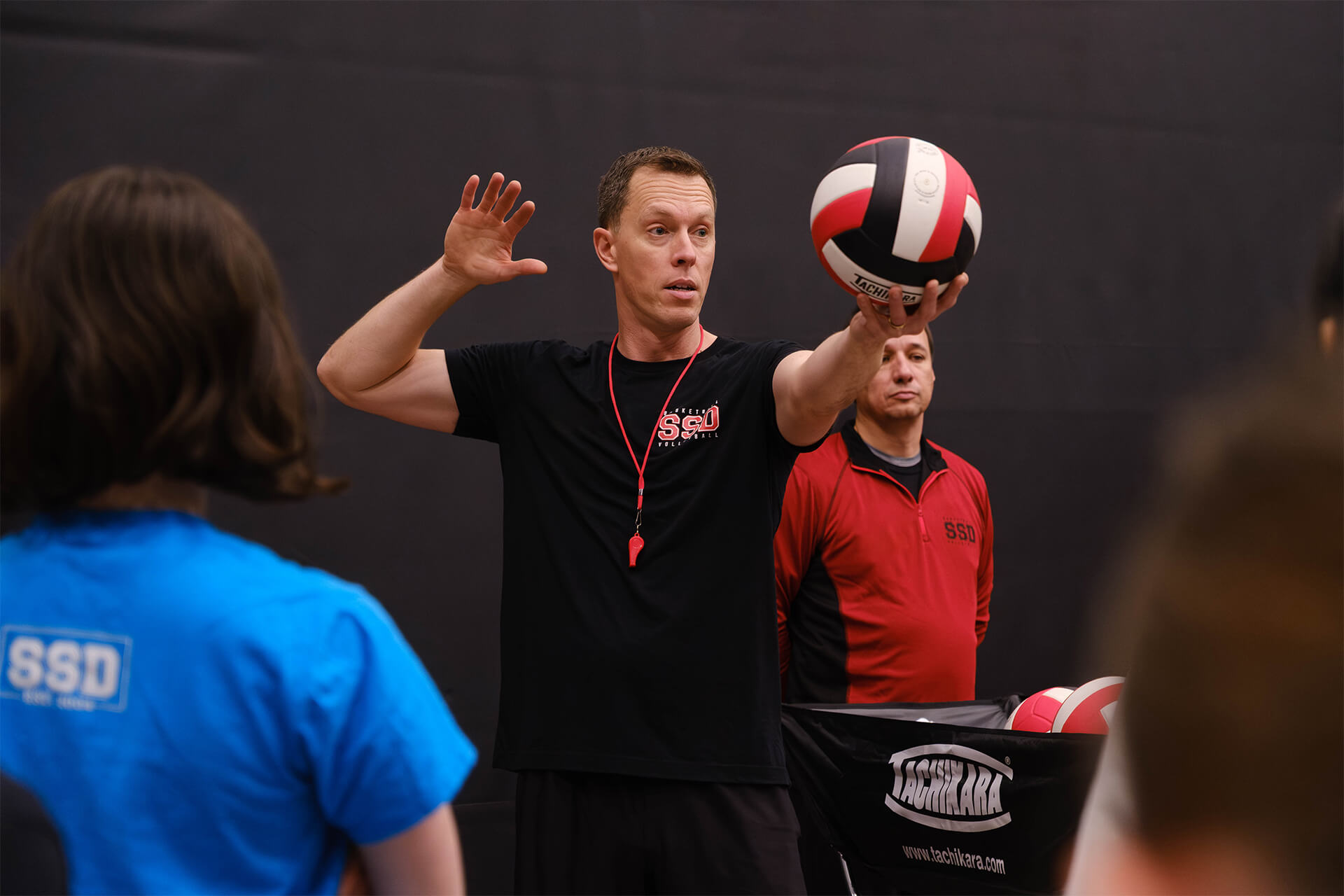 Stryker Sports coach demonstrating volleyball serving technique during athlete development clinic.