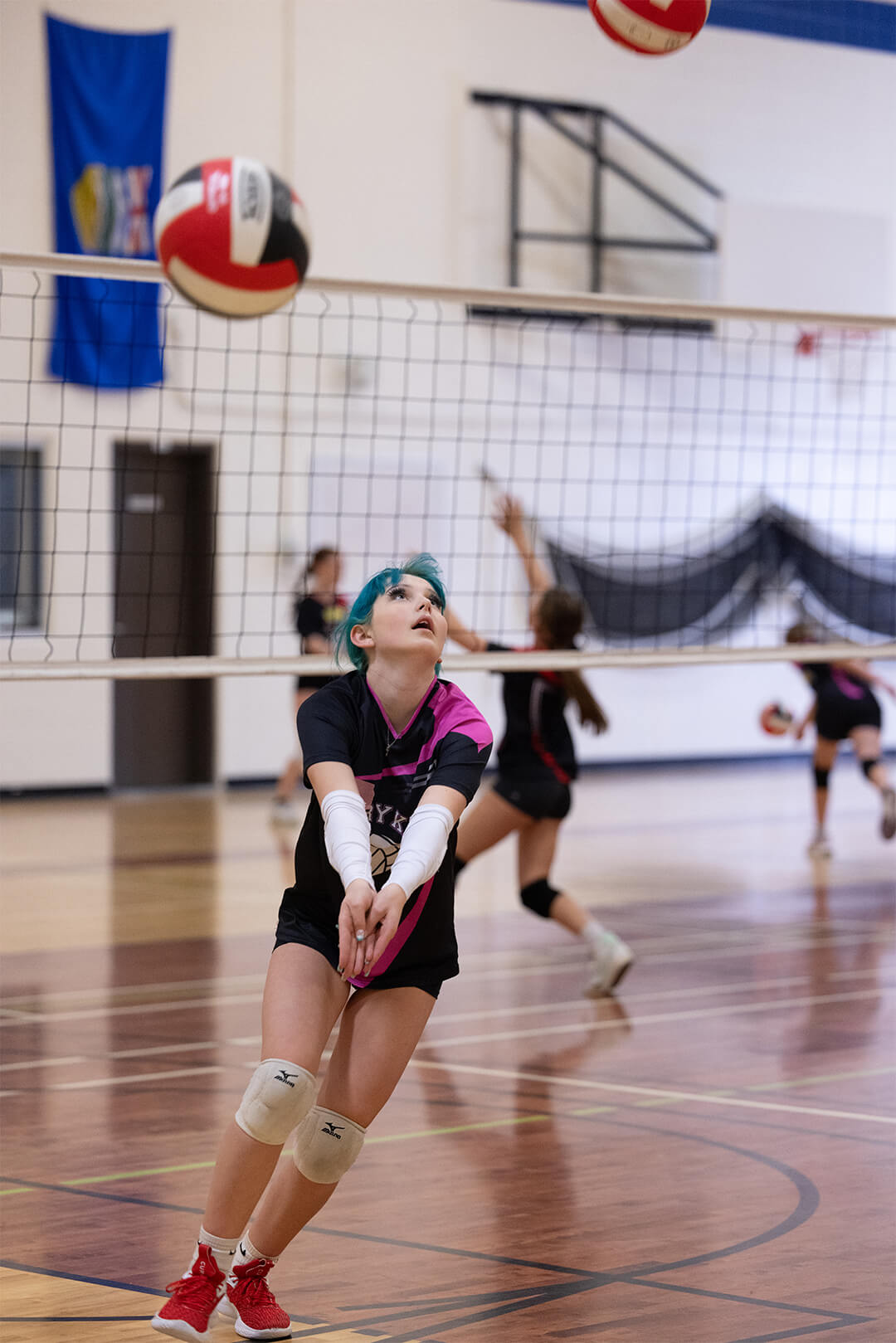 Youth volleyball player tracking ball during competitive practice session.