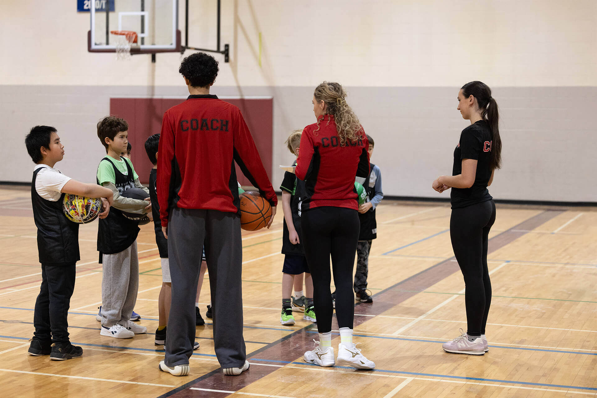 Youth basketball team huddle led by coaches during Stryker Sports training session.