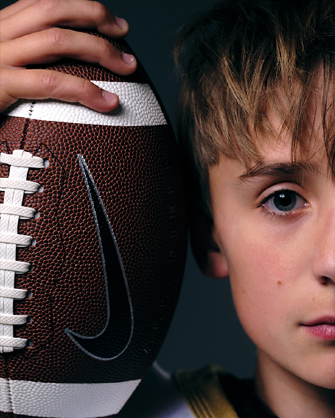 Detail portrait of youth football player holding ball during studio development project.