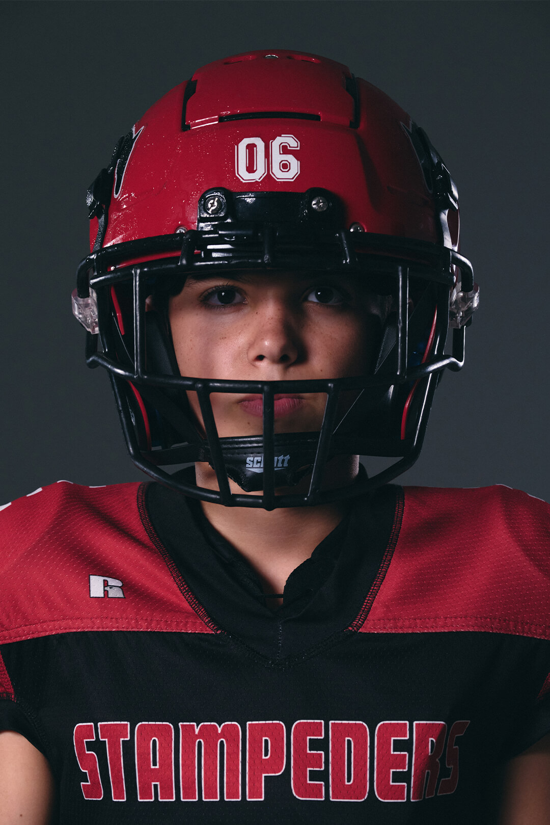 Close-up studio portrait of Calgary youth tackle football athlete in Stampeders jersey.