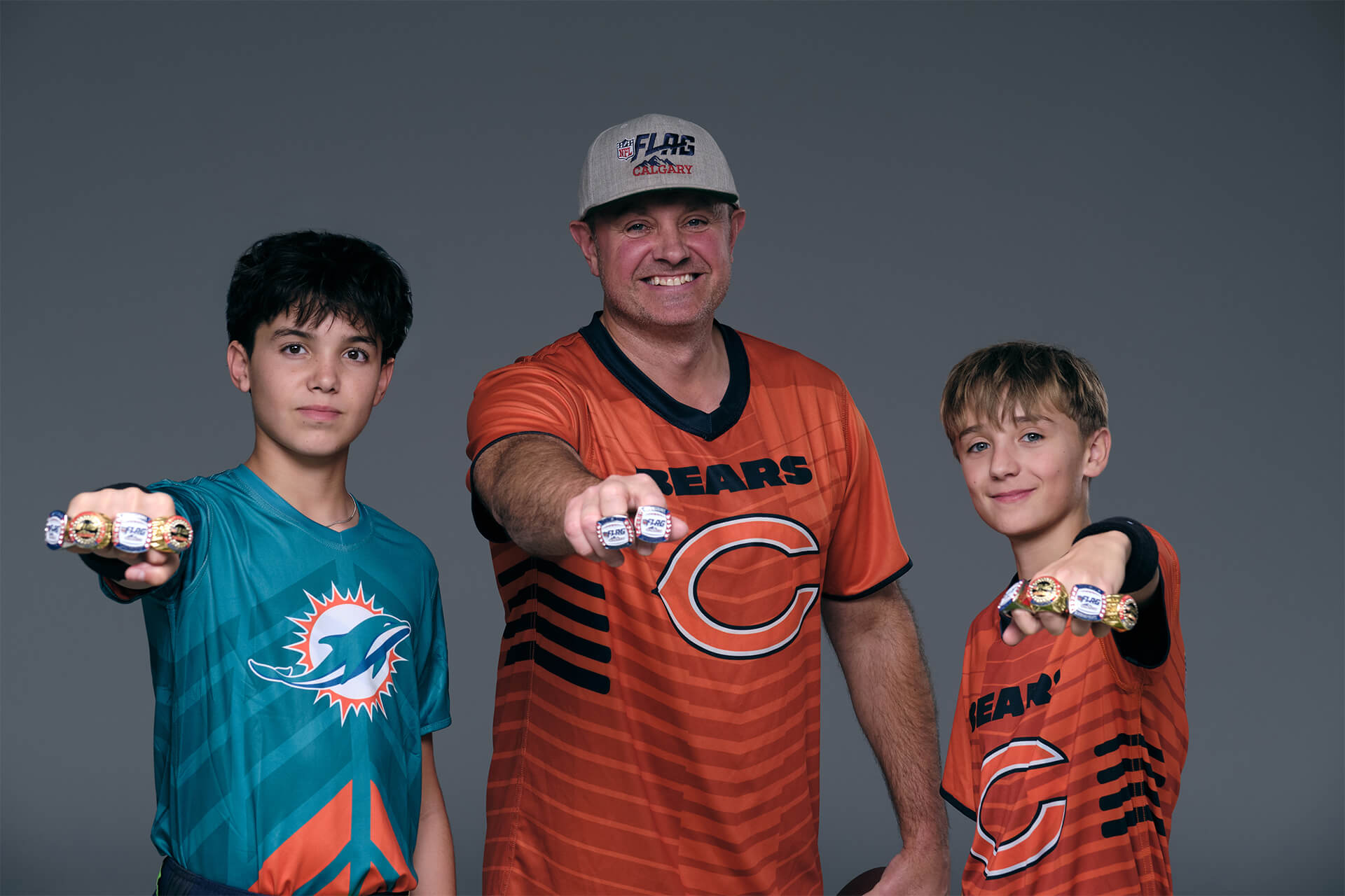 Community-based youth football studio portrait featuring coach and NFL Flag athletes.