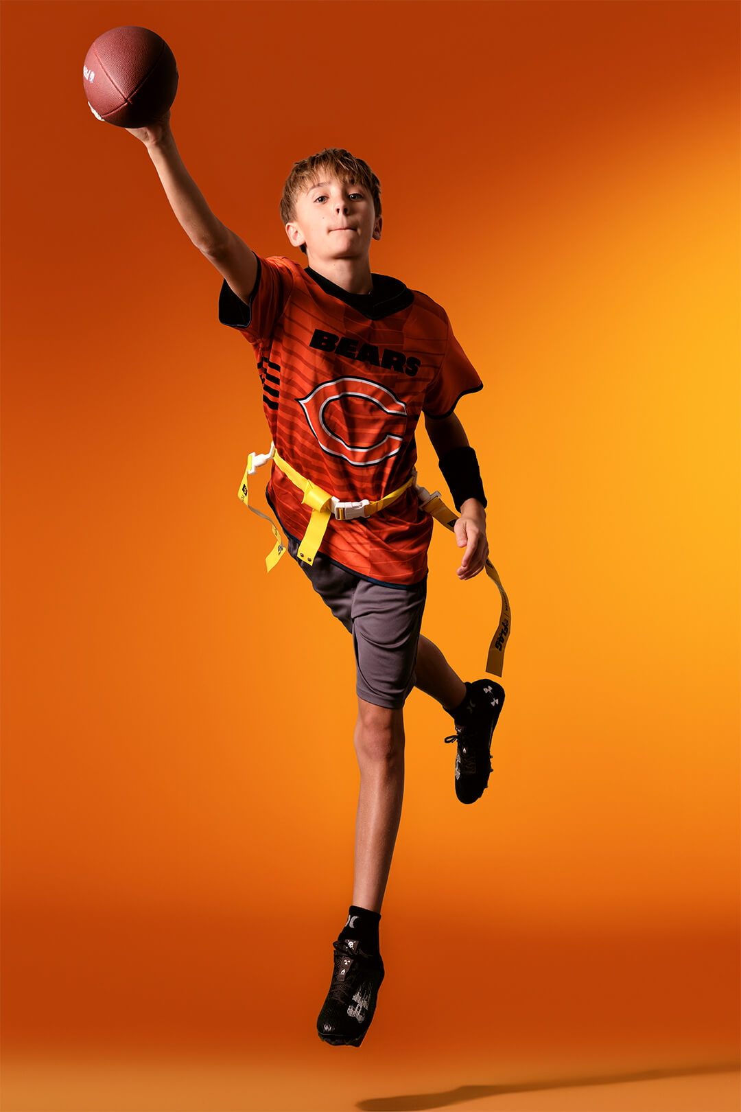 Youth flag football athlete in dynamic studio pose highlighting early-stage sport development.