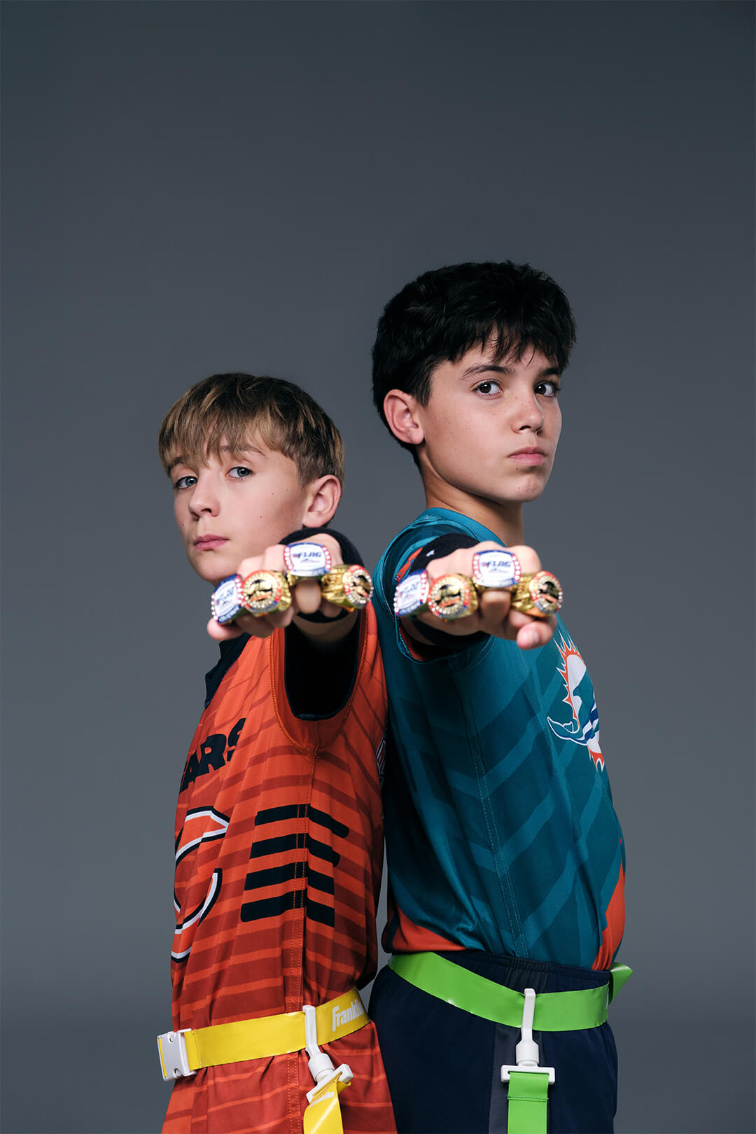 NFL Flag youth athletes posing with championship rings during studio football photography session.