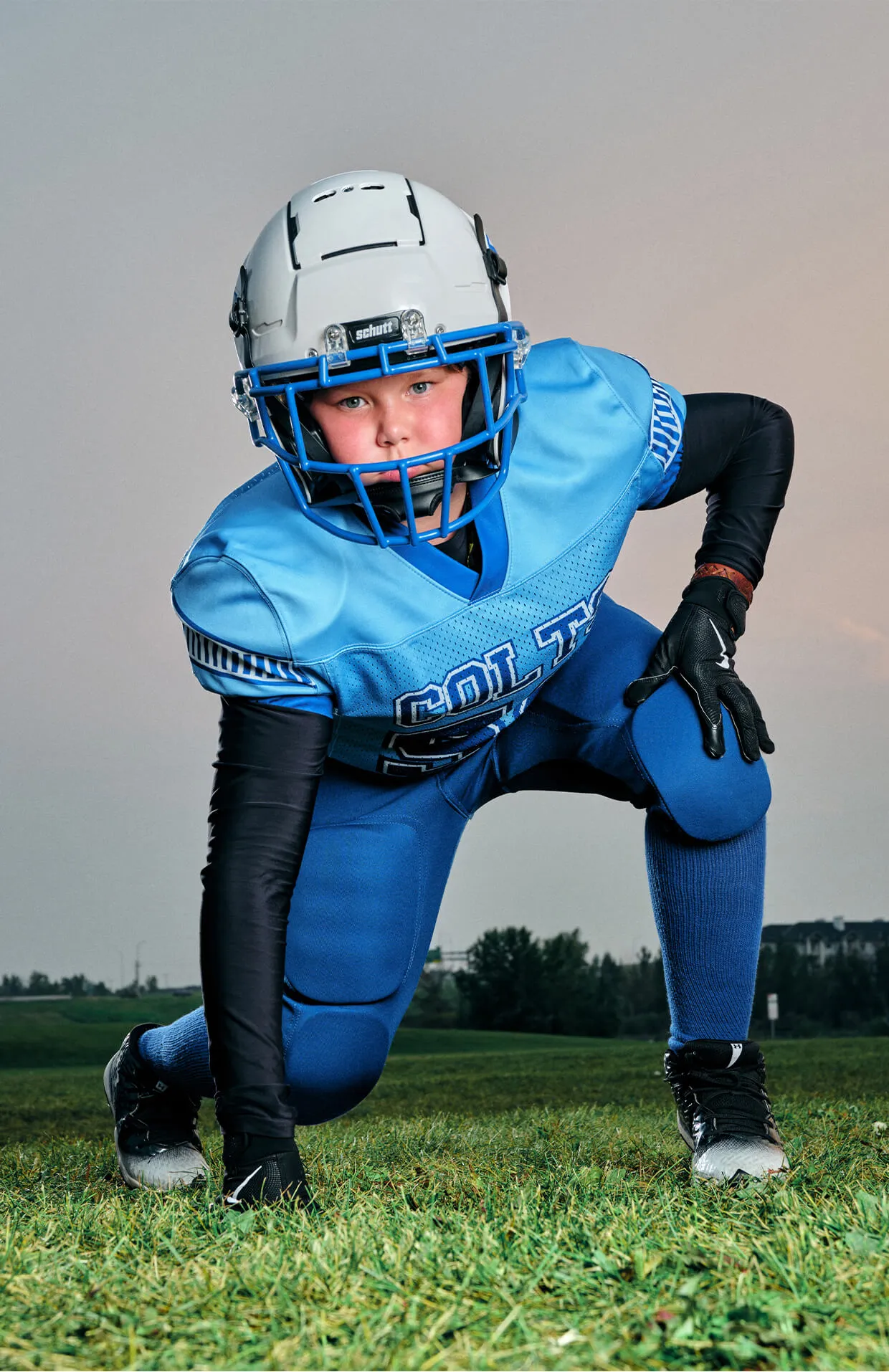 Dynamic low-angle football portrait of youth athlete in game-ready stance.