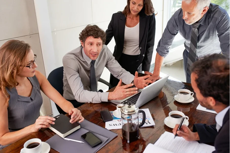 Mitarbeitern versammeln sich um einen Tisch und diskutieren nächste Schritte im Projekt