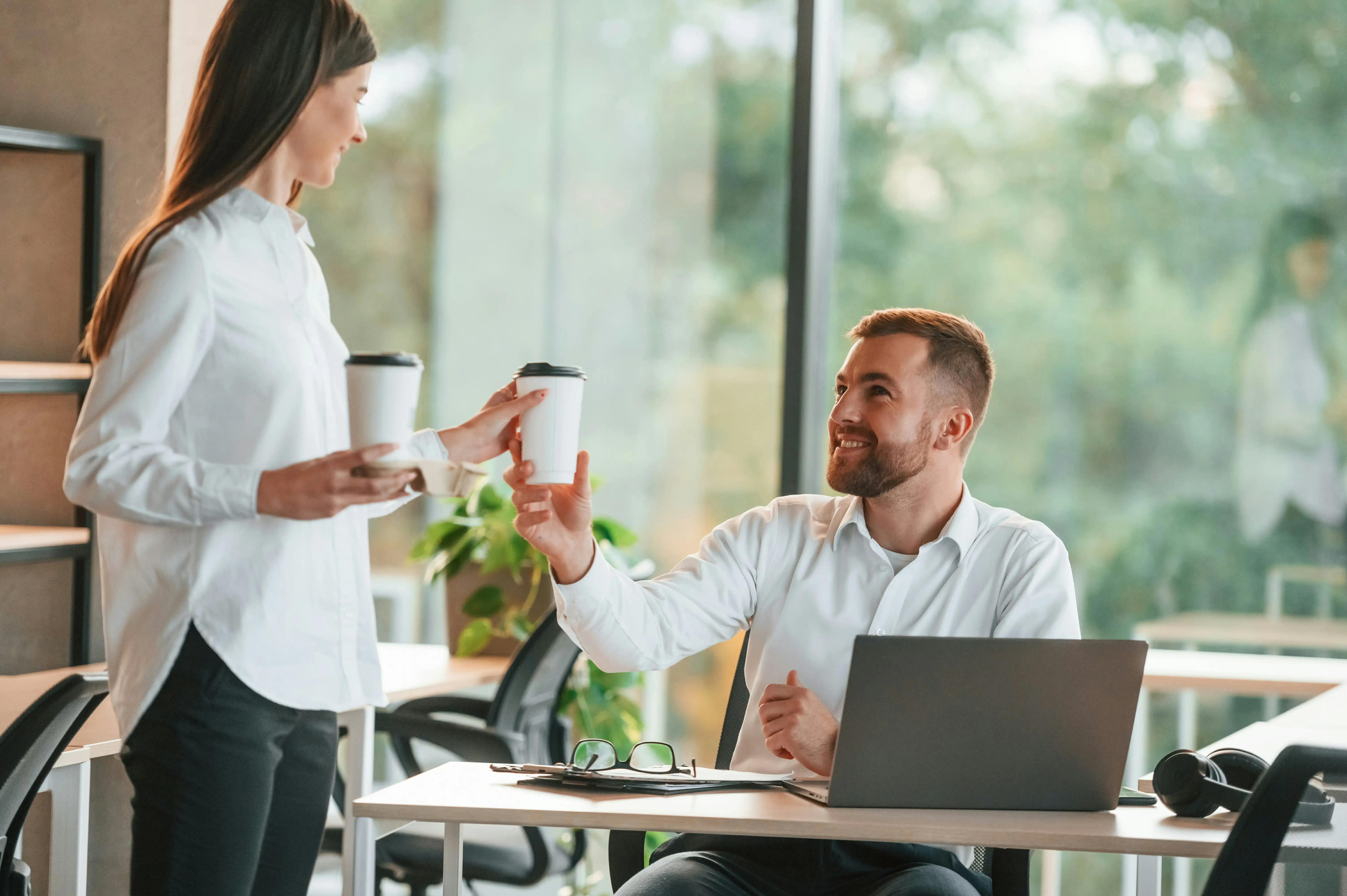Mitarbeiterin reicht ihrem Kollegen einen Kaffee